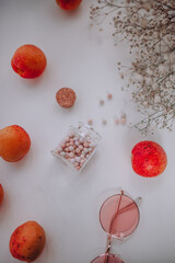 women's cosmetics, rose-colored glasses, peaches, apricots and flowers on a white background