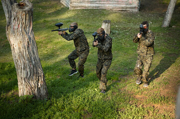 Team in uniform playing paintball in the forest
