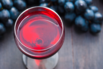 glass of red wine and grapes on black wooden table background
