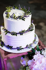 Bunk white cream cake decorated with lavender-style flowers. Trends for wedding desserts.