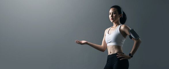Portrait beautiful athlete Asian woman in sportswear show empty hand in studio on  banner grey...