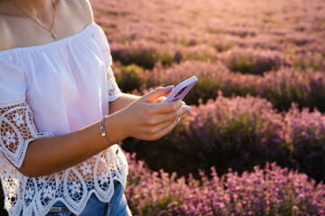 The girl holds a smartphone in a purple case in her hands. Vertical image.