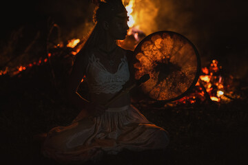 beautiful shamanic girl playing on shaman frame drum in the nature.