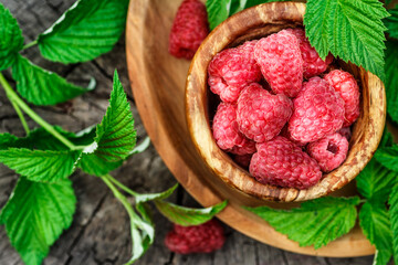 Fresh juicy raspberries in wooden bowl. Summer still life with raspberries on an old wooden table....