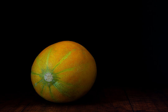 Muskmelon (Israel cantaloupe or Ha Ogen variety) is lying on a rustic weathered wood planks background.