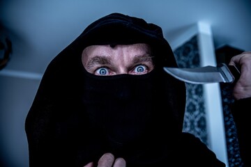 The masked man attacks the victim with a knife. Crime. Horror scene.