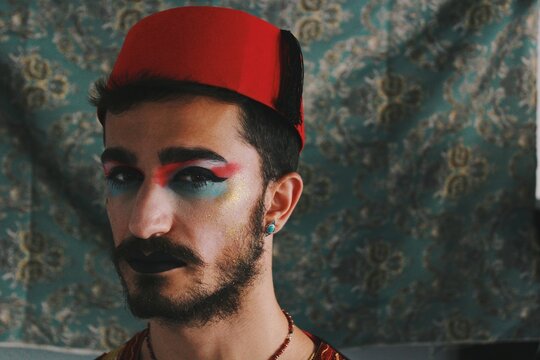 Portrait of queer young man with full face drag makeup & turkish anatolian ottoman traditional clothing with authentic patterns background *4
