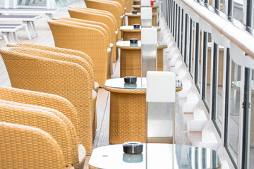 Vue de tables et fauteuils avec cendriers sur le pont d'un navire de croisières.