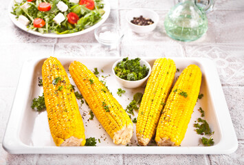 Baked grilled sweet corn cobs with herbs, butter on the white tray