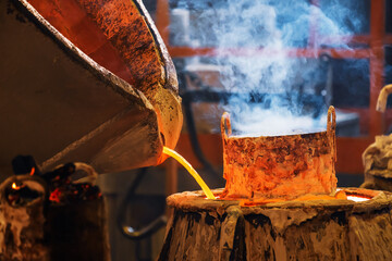 pouring molten red metal into a mold from which smoke is emitted