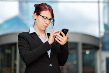 Obraz na płótnie Canvas Smiling businesswoman using a smartphone outdoor