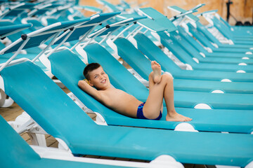 A little boy is smiling happily and sunbathing on a sun lounger on a sunny day. Happy vacation vacation. Summer holidays and tourism. © Andrii