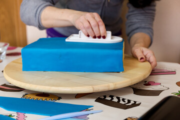 Woman hands smoothing fondant for cake decoration