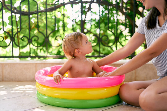 Little girl sits in an inflatable pool and looks at mom