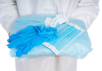 close-up. hands in a white coat are holding a set of personal protection. disposable overalls, mask, gloves. isolated white background