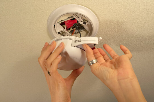Closeup of putting a new 9 volt battery in a home or business smoke detector alarm as the maintenance manual says to do every year.
