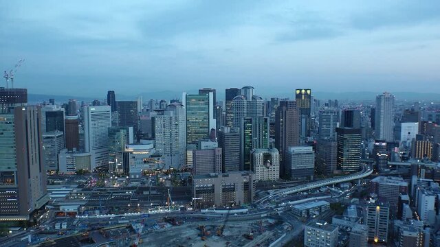 UMEDA, OSAKA, JAPAN : Aerial high angle sunset view of CITYSCAPE of OSAKA. View of buildings and street around Osaka and Umeda station. Wide view time lapse shot, dusk to night.