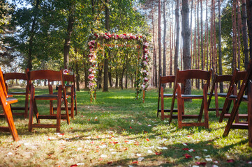 wedding arch  in green forest decorated with flowers.