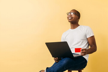 Young African American man with a laptop holding a credit card. concept online shopping and technology