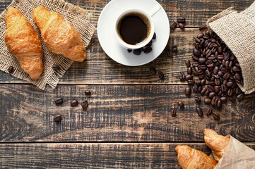 Croissants and coffee on a rustic wooden background with copyspace. Traditional breakfast concept. Top view, flat lay.