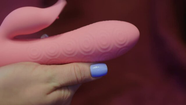 Woman in bedroom holding vibrator in hand.
