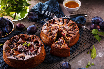 rustic plum cake on dark background , top view