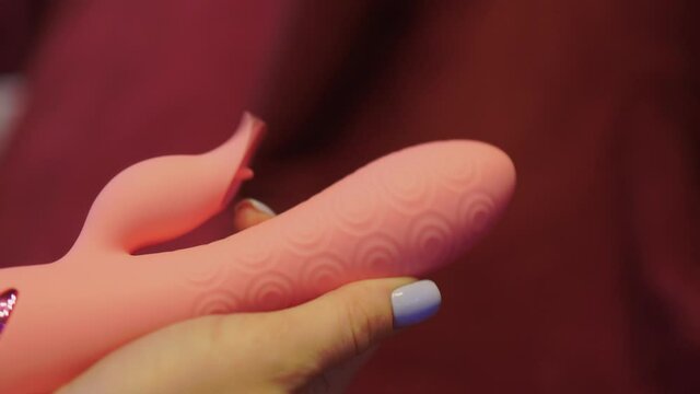 Woman in bedroom holding vibrator in hand.
