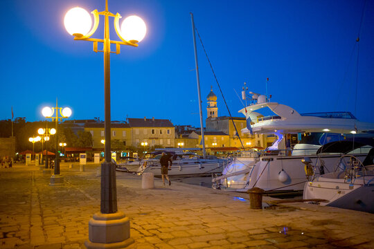 Evening view of Krk Harbor and marina in medieval old town Krk. Mooring yachts, boats and other vessels on the pier. A summer vacation in a Croatian islands at Adriatic sea. Island Krk, Croatia.