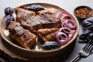 Catfish kebab. Shashlik with roasted fish on on a round plate with red onion and basil.
