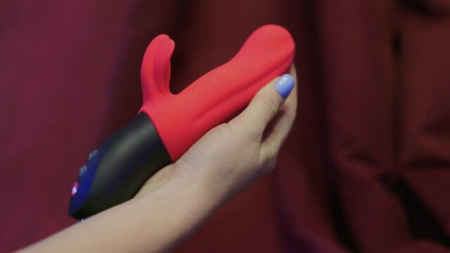 Woman in bedroom holding vibrator in hand.