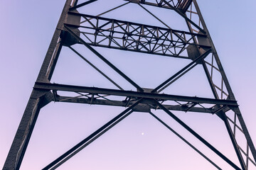 Close-up of a steel construction of a mine shaft tower against morning sky and the moon.