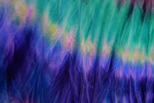 Abstract painted background. Multi-colored pattern in the shibori technique on a thin knitted fabric. Multi-color texture. Batik.Textile shibori