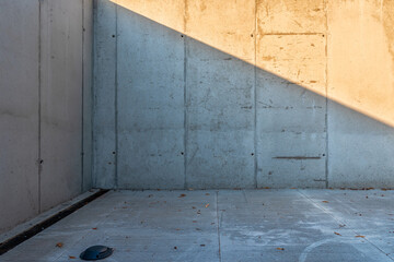 Empty corner outside the building, walls and floor made of concrete. Linear drain situated in...