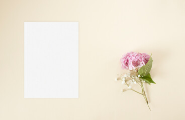 Mockup blank wedding invitation with pink hydrangea and gypsophila flowers on the beige background
