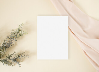 Flat lay mockup wedding invitation with eucalyptus and nude fabric on the beige background
