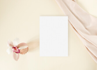 Flat lay mockup greeting card with lily and nude fabric on the beige background
