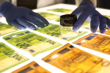 Hand with magnifying glass checks authenticity of money