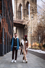 Young caucasian couple of tourists walk at Brooklyn bridge in New York city. Cheerful man and...