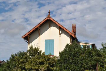 Gable on Old French Farmhouse Building against Cloudy Blue Sky 