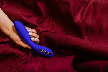 Woman in bedroom holding vibrator in hand.