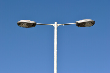 Isolated Steel Lighting Pole with Two Modern Lamps against Blue Sky