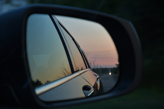 Soft focus view from car window with road reflection into side mirror. Dusky blurred reflection while driving in evening. Road trip in blue purple dusk © Ninel