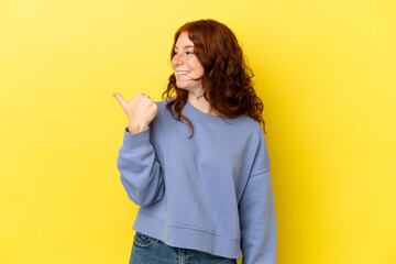 Teenager reddish woman isolated on yellow background pointing to the side to present a product