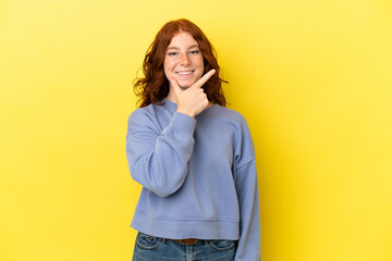 Teenager reddish woman isolated on yellow background happy and smiling