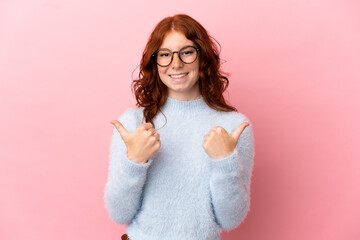 Teenager reddish woman isolated on pink background with thumbs up gesture and smiling