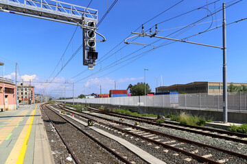Fototapeta premium Perspective of Railway track with platform, rails and electric lines against Blue Sky. Italy