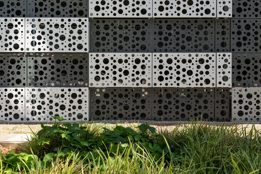 Background image of a perforated facade with a green foreground