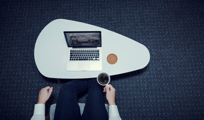 Businessman works alone from his home office and drinks coffee. View from above in a horizontal composition.