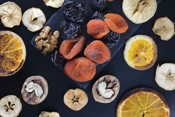  Mixed nuts and dried fruits on a slate dish on a dark background, top view, banner. Healthy snack-a mixture of organic nuts and dried fruits