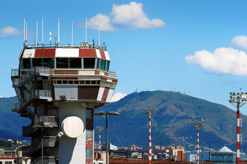 Air traffic control tower at Genoa Airport against mountain and blue sky. Genoa, Italy